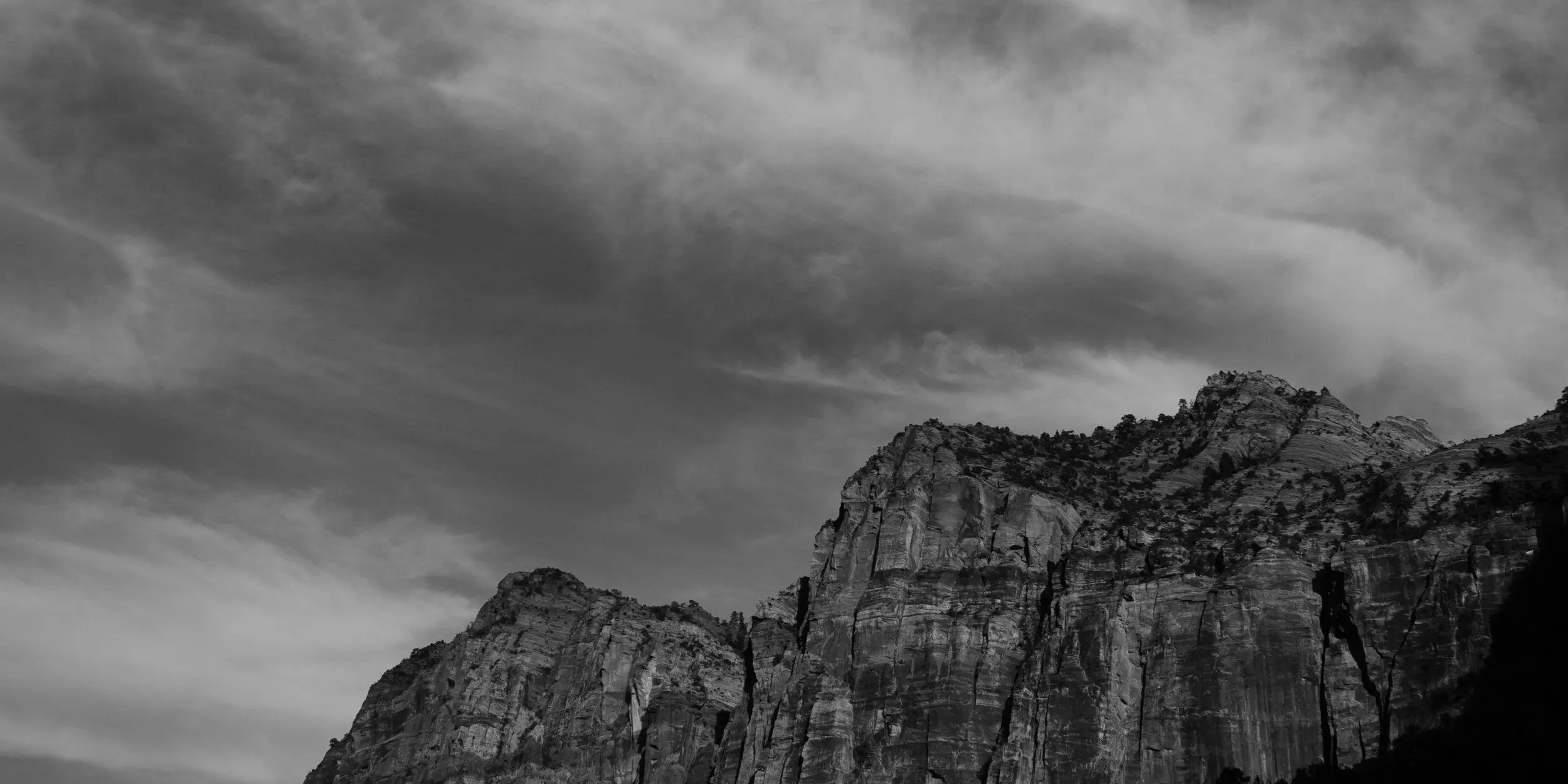 Black and white mountains under dramatic clouds through the Zion – Mount Carmel Highway.