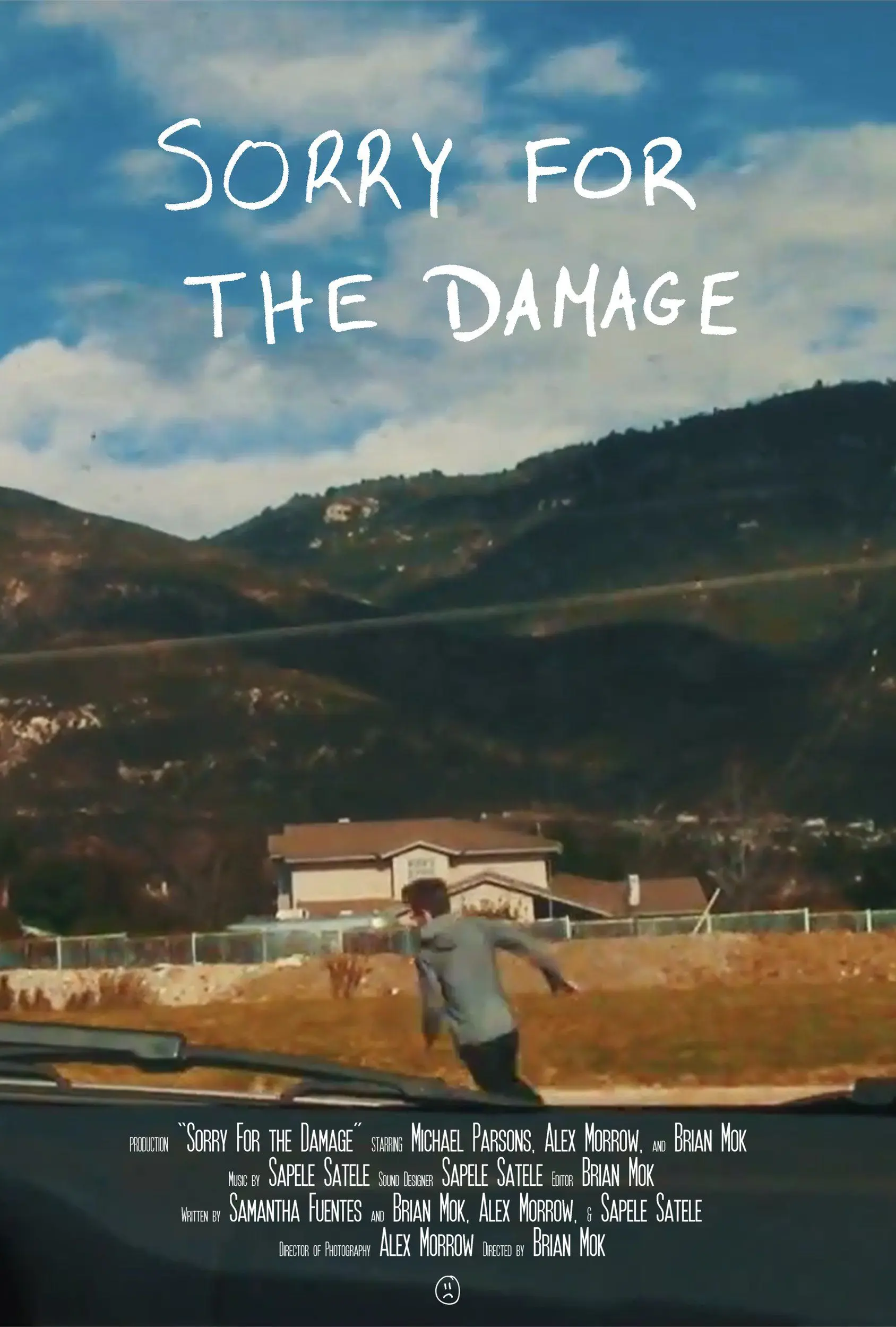 "Sorry For the Damage" film poster. A man runs away from a car that we are in with a house and mountains in the background.
