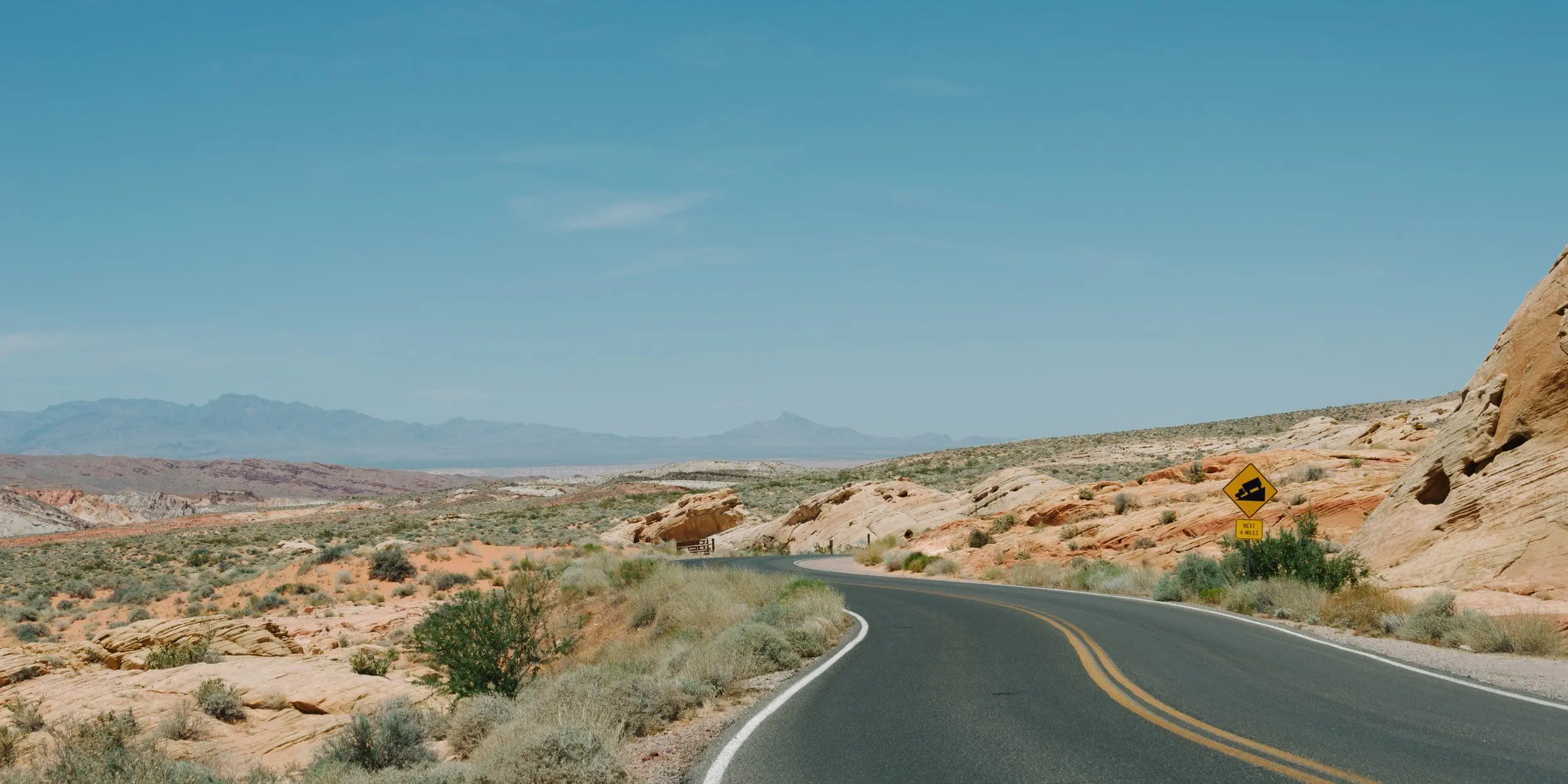 An empty road curves through the Valley of Fire. Midday.