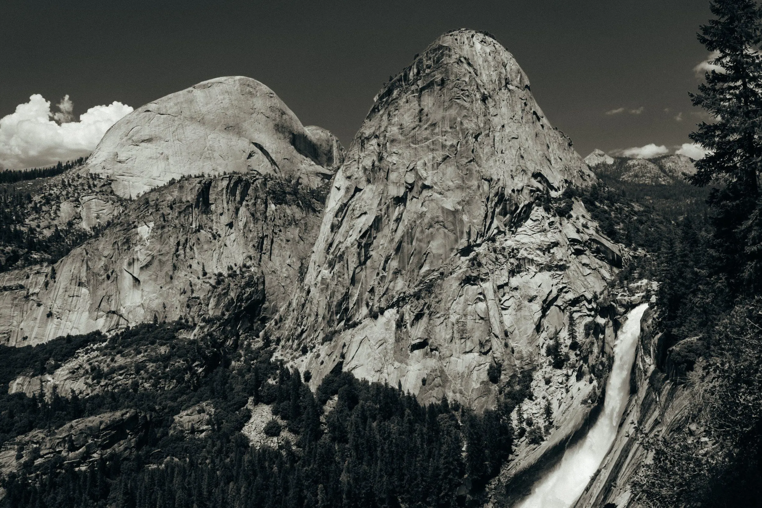 Wide aerial monochromatic shot of Half Dome, Mount Broderick, Liberty Cap, and Nevada Fall.